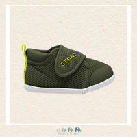 Green children's shoe with a strap on a beige background