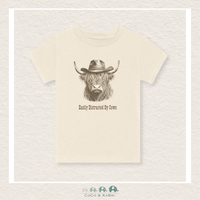 Beige t-shirt with a graphic of a cow wearing a cowboy hat and text 'Easily Distracted By Cows' on a textured beige background.